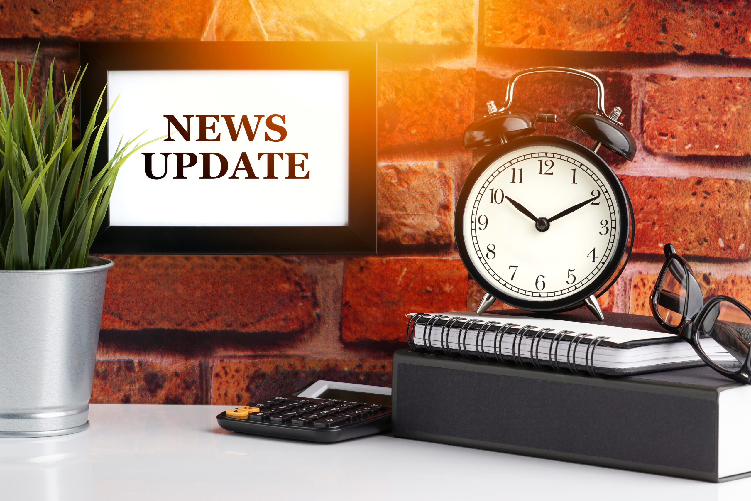 NEWS UPDATE text with alarm clock, books and vase on brick background. Business, Quotes and Copy Space concept